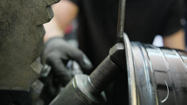 Car alloy wheel repair. Mechanic uses hydraulic device to align car rim, close-up