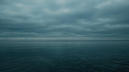 Obraz premium Vast expanse of a calm sea under a moody sky.