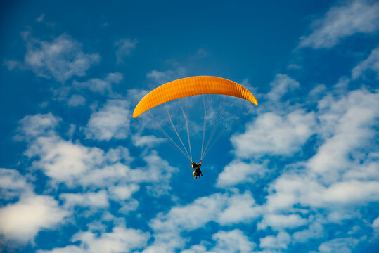paragliding, yellow parapente on the blue sky.