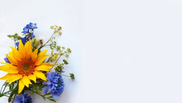 A summer bouquet with a yellow sunflower on a white background. A festive bouquet. The background for the postcard.