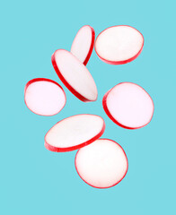 Fresh ripe radish pieces falling on light blue background