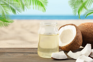 Cooking oil in jar and coconuts on wooden table against beach. Space for text