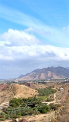 Hatta, UAE - March 2, 2025:Mountains rise behind green oasis palms under vivid sky where mountains form natural boundary around fertile desert village, attracting every tourist with contrast