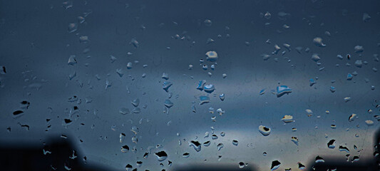 Rain drops on glass in the evening wallpaper background