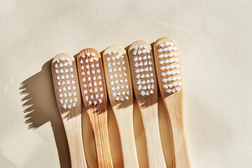 Eco-friendly wood toothbrushes with white bristles at sunlight on beige background. Minimal trend design photo, sustainable hygiene concept, Zero waste lifestyle, eco-conscious living, dark shadow