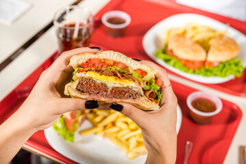 hands holding sandwich in diner environment, fast food concept