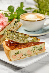 Delicious homemade quiche with salmon and spinach filling enjoyed with cappuccino