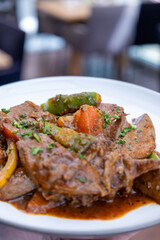 A plate of meat with Potato and herbs