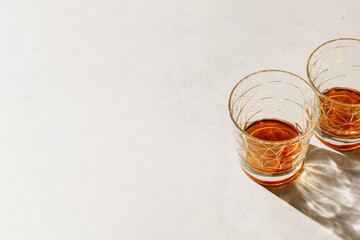 Transparent alcohol Glasses with shadow at sunlight on beige concrete table, top view minimal style, aesthetic photo shiny glass sparkling at natural light, summer strong drink, still life