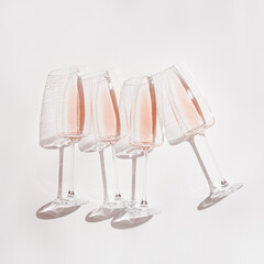 Rose wine in transparent stemmed glasses, minimal style still life, top view rose sparkling wine with sunlight and shadows. Summer light alcoholic drink on white background, copy space