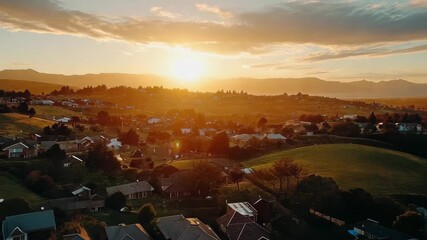 Stunning drone aerial view of suburban neighborhood during golden hour sunset, Beautiful drone shot flying over suburban homes and hills sunset glow