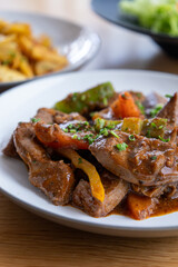 A plate of meat with Potato and herbs