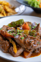 A plate of meat with Potato and herbs