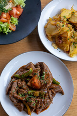 A plate of meat with Potato and herbs