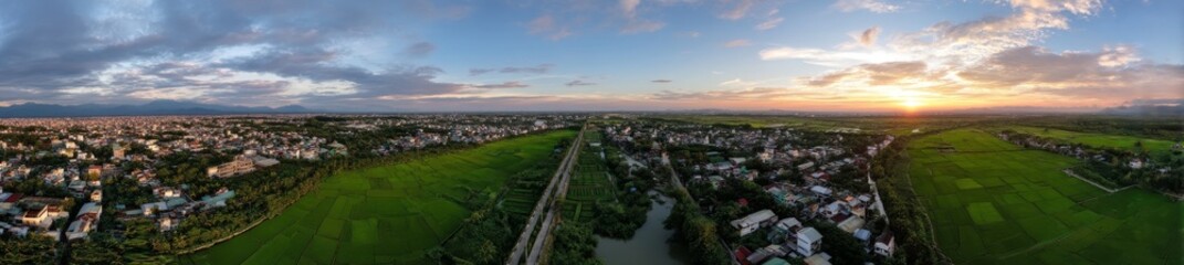 Exterior of agricultural silos for storing and drying grains like wheat, corn, soy, and sunflower set against a blue sky with surrounding rice fields