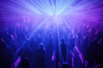 A large crowd enjoys a vibrant concert bathed in purple and blue laser lights, creating a dynamic and energetic atmosphere.