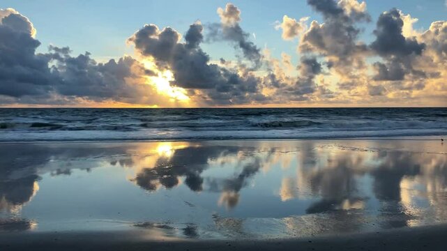 A shallow layer of water creates a spectacular mirror-like reflection of the sky and clouds. Amelia Island, Florida, USA.