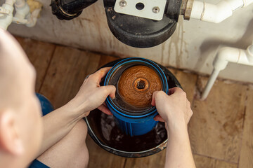Man changes a cartridge in a water filtration and purification system. Dirty cartridge