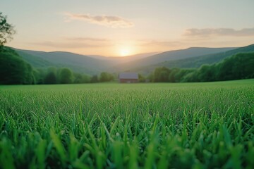 Sunset over green field with barn and mountains.