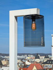 Modern lamp with glass shade against clear blue sky.