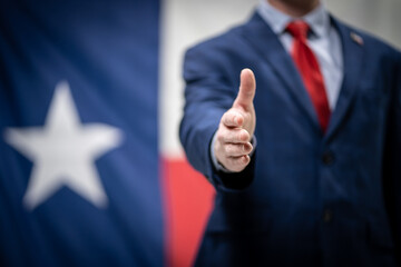 Businessman Politician Wearing Suit Jacket and Tie Holding Out Hand for Handshake With Texas Flag...