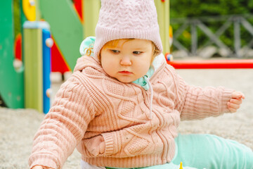 A young child wearing a knitted hat and cozy sweater explores a vibrant playground The setting features bright colors and a cheerful atmosphere perfect for outdoor fun