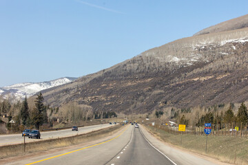 Vehicles cruise westbound on Colorado’s I-70, surrounded by majestic snow-dusted peaks and alpine landscapes near Vail Pass