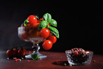 Healthy cherry tomatoes with basil in ribbed bowl on dark background, ideal for vegan diet and...