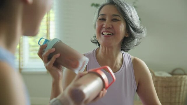 Young adult child active mature middle age old mum drink whey protein shake bottle diet food after home workout. Love health care older aged mom asia elder people happy relax sport protect aging life.