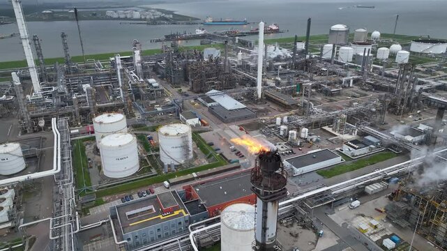 Aerial view of a chemical plant at sunset. Drone shot. Curling fire and cumin smoke filling the sky. Smoking chimneys from the factory. Chimneys of an oil refinery at sunrise pollute the environment