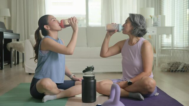 Young adult child active mature middle age old mum drink whey protein shake bottle diet food after home workout. Love health care older aged mom asia elder people happy relax sport protect aging life.