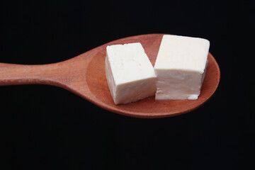 tofu with wooden spoon on a black background