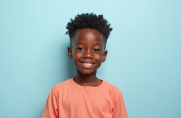 Smiling African American little boy on blue background. Happy child looking at camera. Cute young boy with curly hair. Portrait of cheerful kid. Joyful positive face expression.