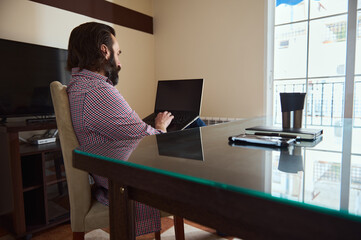 Focused Professional Working on Laptop at a Sunlit Home Office Desk