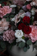 Delicate pink preserved flowers in a vase, in a dark interior. Tall black candles and warm light. An atmosphere of coziness and luxury. Women's day, mother's day, valentine's day.
