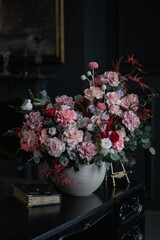 Luxurious bouquet of preserved flowers with roses on black table and dark background.