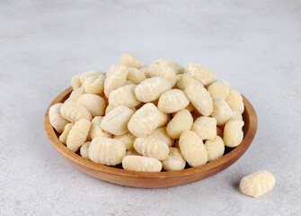 Italian potato gnocchi on wooden plate on grey background. Italian pasta.