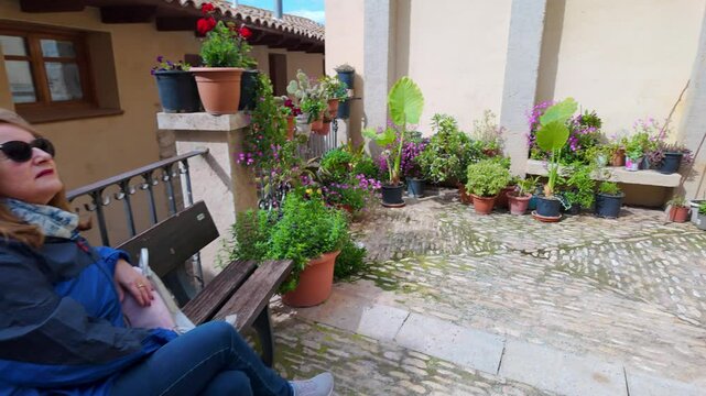 Tourist woman resting on a bench and surrounded by plants and flowers in the beautiful village of Valderrobres, Teruel.