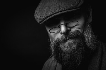 Black and white, Macro portrait of a serious bearded man in a cap and glasses on a black...