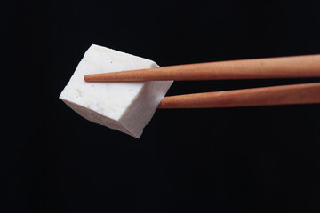 Pick up tofu with chopsticks on a black background
