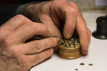mains d'un horloger en train de réparer une horloge, un mécanisme d'horlogerie