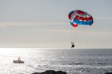 Parasailing or parascending recreational water sport with boat on Tenerife, Costa de Adeje, adventure for tourists