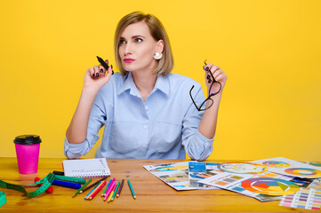 creative woman designing at desk surrounded by colorful pencils, charts, and coffee against vibrant...