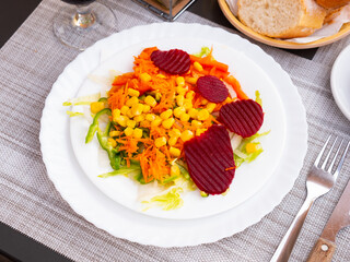 Appetizing light vegetable salad made from corn, sliced beetroot, bell pepper, grated carrots and onions