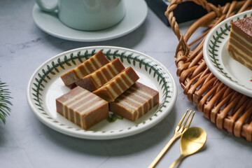 A traditional Indonesian steamed layer cake with alternating vibrant layers, showcasing a soft,...