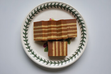 A traditional Indonesian steamed layer cake with alternating vibrant layers, showcasing a soft, moist texture and rich flavors, perfect for festive occasions.