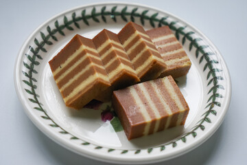 A traditional Indonesian steamed layer cake with alternating vibrant layers, showcasing a soft, moist texture and rich flavors, perfect for festive occasions.