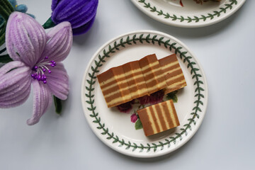 A traditional Indonesian steamed layer cake with alternating vibrant layers, showcasing a soft, moist texture and rich flavors, perfect for festive occasions.
