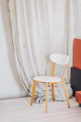 Charming minimalist corner featuring a sleek white chair and soft fabric drapery in a cozy indoor setting during daylight hours