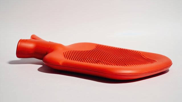 An orange racket, possibly for tennis or badminton, with a textured handle and an adjustable string tension.